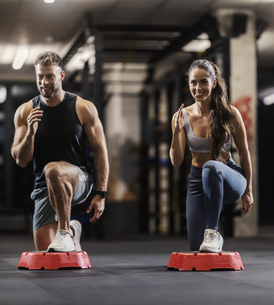 A muscular couple in shape is exercising gluteus and legs in a gym.
